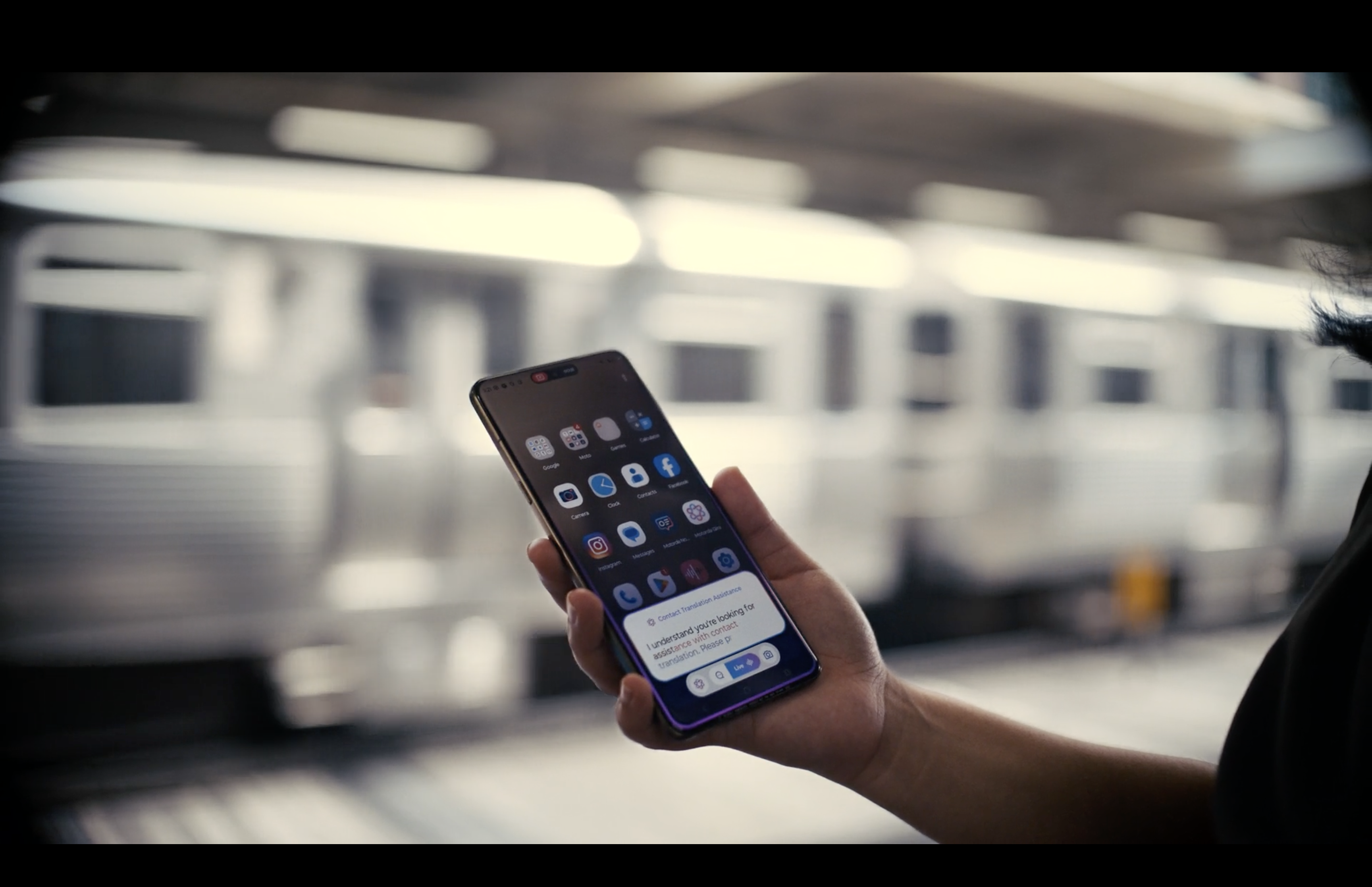 A person holding a smartphone on a train platform
